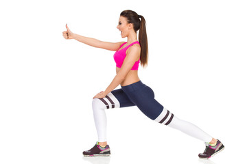 Fitness woman doing lunges exercises and showing thumb up.