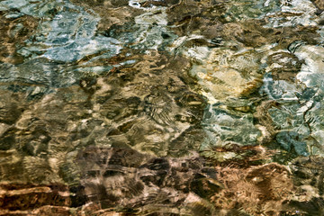 Clear creek water with stones at the bottom. Background of stones. Pebbles under water texture. Underwater in spring water, close-up.