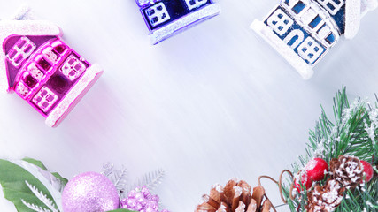 Holiday decorations on fir branch. Christmas decorations on white background. Pine cone and red berries on fir branch. Purple ball and colorful toy houses. Widescreen