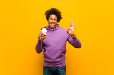young african american man with a light bulb against orange back