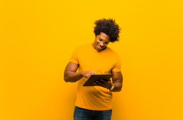 young african american man with a tablet against orange backgrou
