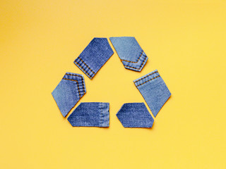 Reuse, reduce, recycle concept background. Recycle symbol made from old jeans on yellow background....