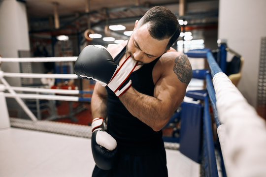 young strong man taking off boxing gloves after workout, cclose up photo.
