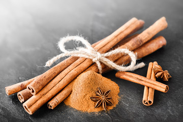 Cinnamons sticks on dark stone table. Dried cinnamon powder with star anise on black board.