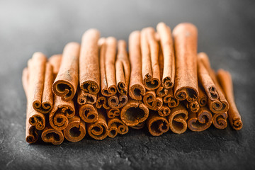 Fresh dried cinnamon tree or sticks on dark stone table. Pile of cinnamons on table.