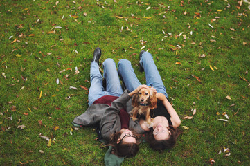 Woman with american cocker spaniel plays at autumn park