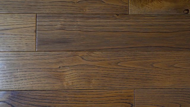 Close-up brown walnut Board floor hardwood parquet close-up with beautiful texture in interior, camera slide from left to right
