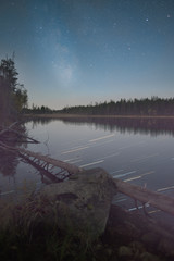 Stary night sky with lake and forest reflection
