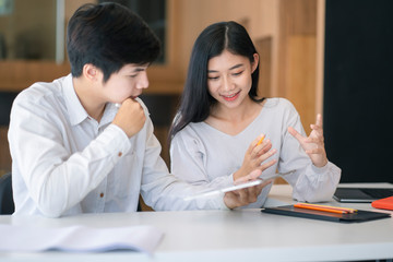Young Asian couple or college student using digital tablet and laptop computer notebook work together at coffee shop or university campus.