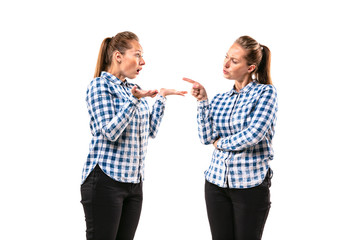 Young handsome woman arguing with herself on white studio background. Concept of human emotions, expression, mental issues, internal conflict, split personality. Half-length portrait. Negative space.