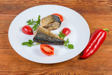Baked mackerel slices, parsley, tomatoes on dish, red pepper