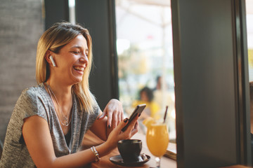 Young beautiful woman relaxing in coffee shop and having video chat via smartphone and drink coffee.