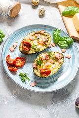 Keto diet: Avocado with ham, quail eggs, cheese on concrete background