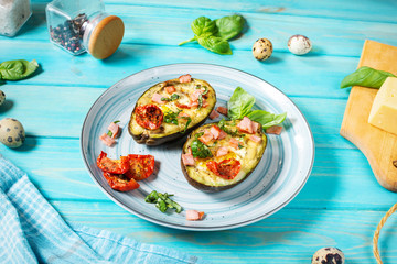 Keto diet: Avocado with ham, quail eggs, cheese on blue wood background