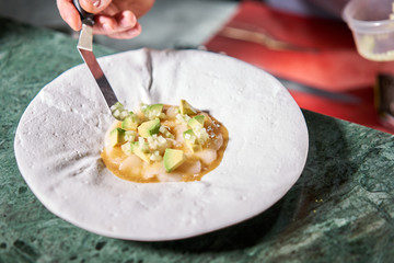 The chef serves the dish Tartar from scallop with avocado, cherry tomatoes, radishes and onion. Dish in the restaurant from raw seafood.