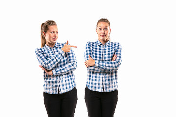 Young handsome woman arguing with herself on white studio background. Concept of human emotions, expression, mental issues, internal conflict, split personality. Half-length portrait. Negative space.