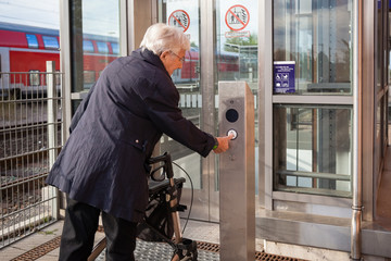 Very old senior woman with walker taking an elevator at the railroad station © sururu
