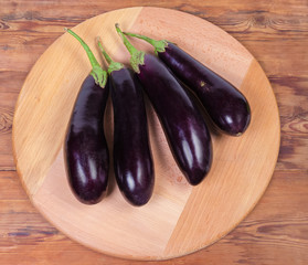 Top view of fresh purple eggplants on wooden serving board