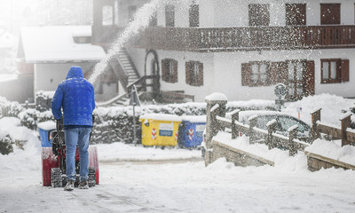 A man removing snow from street with snowblower.