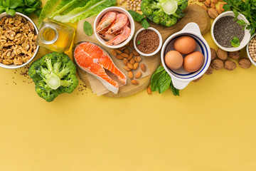 Omega 3 food sources and omega 6 on yellow background top view. Foods high in fatty acids including vegetables, seafood, nut and seeds