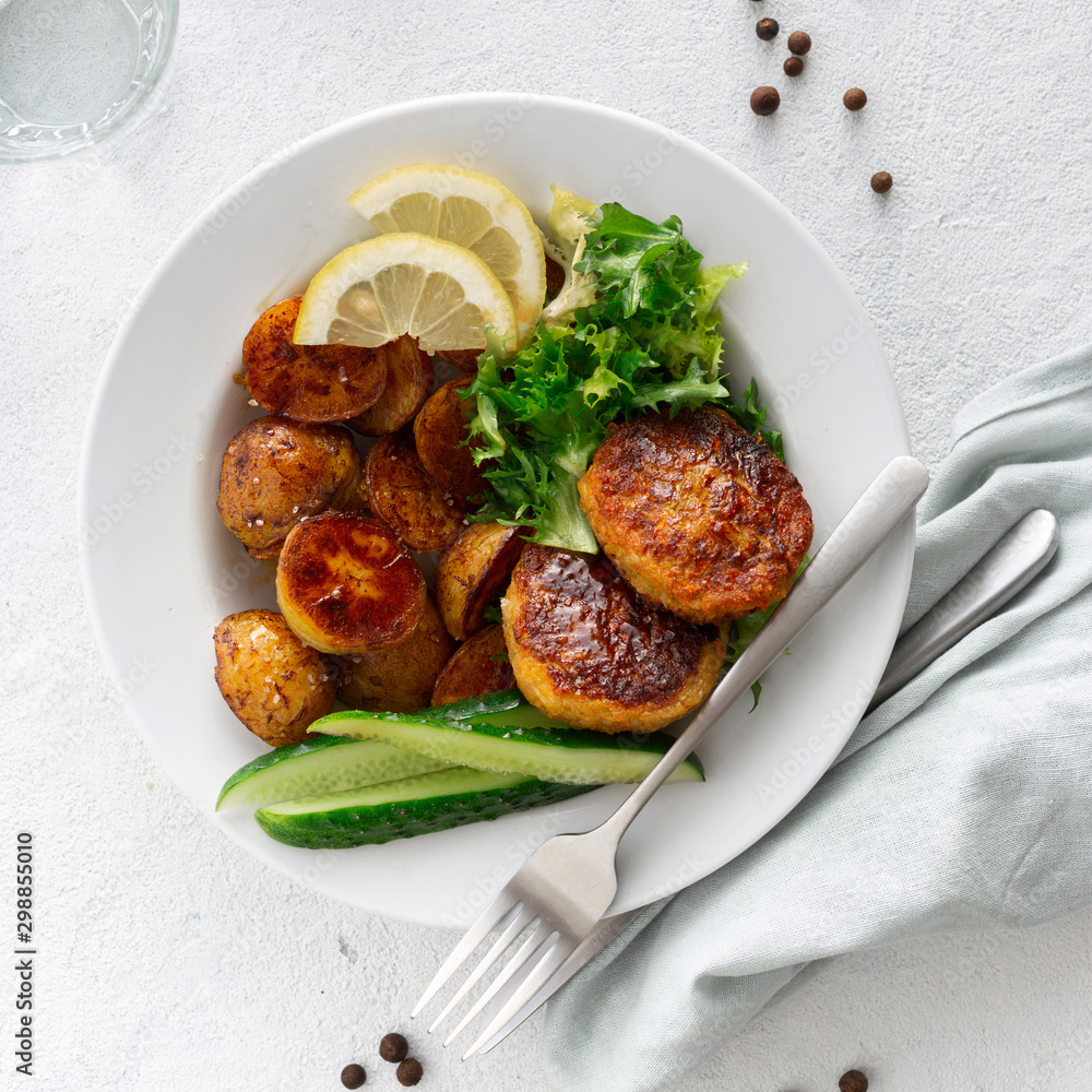 Wall mural Dinner plate with vegetarian food. Fresh vegetarian cutlets with new potatoes and salad on white background top view