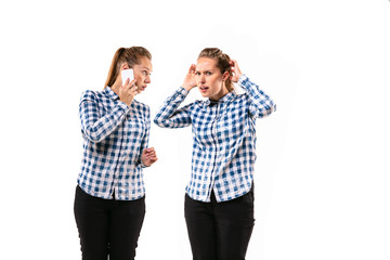 Young handsome woman arguing with herself on white studio background. Concept of human emotions, expression, mental issues, internal conflict, split personality. Half-length portrait. Negative space.