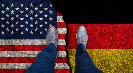 Business man stands on cracked flags of USA and Germany. Political concept
