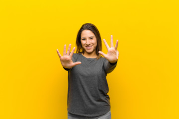latin american woman smiling and looking friendly, showing number nine or ninth with hand forward,...