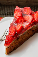 Piece of strawberry cake on white ceramic cake stand.