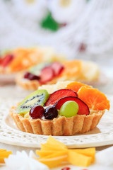 Beautiful cupcakes decorated with fresh fruits: grapes, peach, orange.