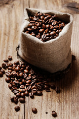 Jute sack of coffee beans on wooden table.
