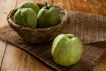 Guava in a wooden basket placed on a wooden floor