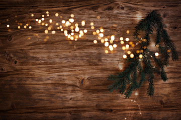 Christmas lights with fir branch on old wood