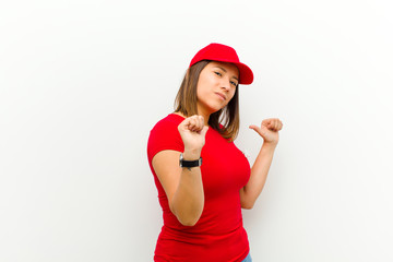 delivery woman feeling proud, arrogant and confident, looking satisfied and successful, pointing to...