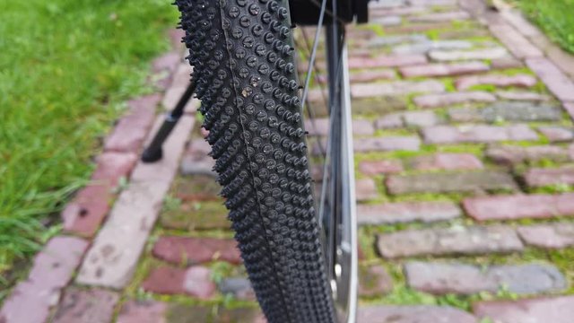 Close up footage of modern and brand new rear bicycle tire of parked cycle panning up camera view also showing the mechanical belt drive and further components on the vehicle 4k high resolution