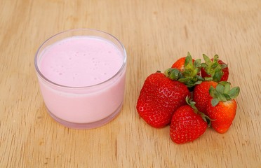 Cup of yogurt and strawberries on wooden background. 