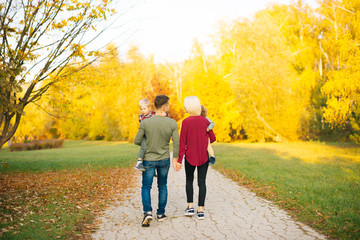 Young happy family with two little boys walking in autumn colorful park
