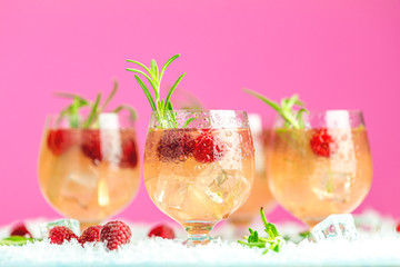 Fresh raspberry cocktail with rosemary and ice in glasses with water drops. Christmas and New Year holiday welcome drink.