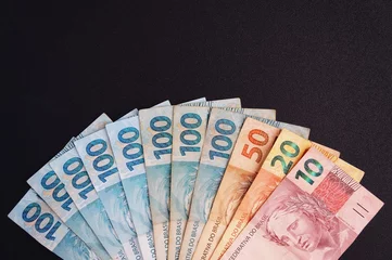 Fotobehang Brazilian money on black background. Real. Brazilian currency.  © Brenda Blossom