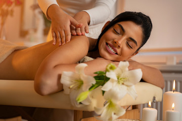 Obraz na płótnie Canvas Dark hair pretty young woman on massage table enjoying her treatment and smiling 