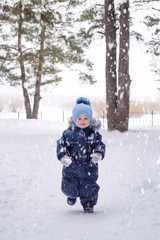 Fototapeta na wymiar A little boy of three years in winter on a walk, snowy weather.