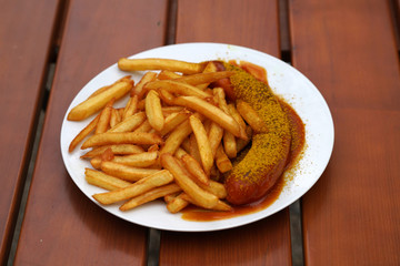 Tasty currywurst with french fries served in a beer garden for immediate consumption