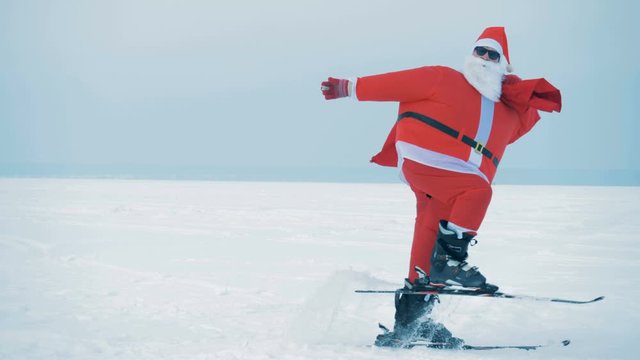 Santa Claus in sunglasses is skiing across the snow