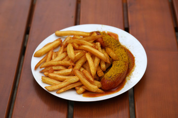 Tasty currywurst with french fries served in a beer garden for immediate consumption