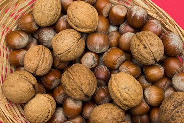 Hazelnuts, walnuts in a basket on a red background