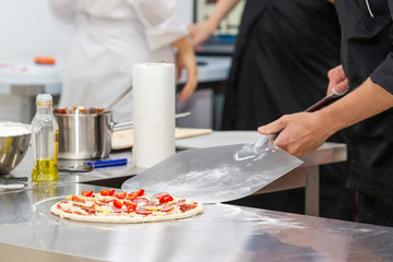 Cook in black uniform preparing pizza