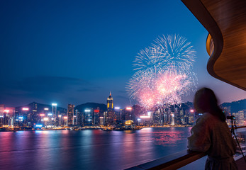 Woman watch firework show at Hong Kong Victoria Harbor  from Deluxe Hotel 