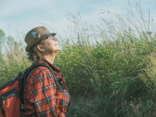 Mature woman in a hat and with a backpack surrounded by nature, active lifestyle of senior people.