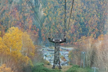 Aerial view from a cable car of Kurodake Ropeway flying over colorful autumn forests with seasonal...