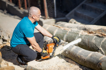 Man cut with saw. Dust and movements. Woodcutter saws tree with chainsaw on sawmill. lumberjack